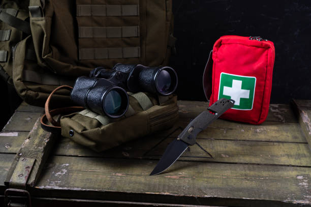 Angle top view on military composition. Army knife with olive handle and black blade. Binoculars for searching. Knife.