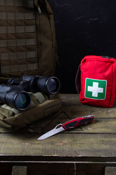 istock Swiss army knife and first aid kit. Binoculars and military backpack on a military box. Vertical frame. 1448379801