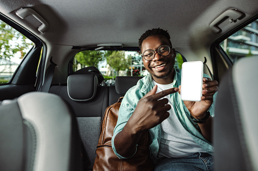 African-American male commuter showing a smart phone in taxi