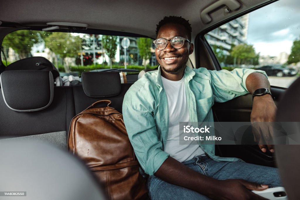 African-American man sitting at the back seat of a taxi African-American male commuter sitting in taxi Taxi Stock Photo