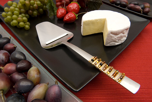 A cheese shaver utensil  on a  party plate  with buffet items
