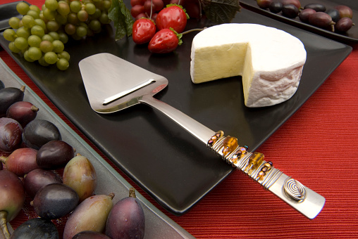 A cheese shaver utensil  on a  party plate  with buffet items