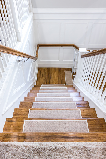 Wood stairs with carpet rug accents for grip with a white painted handrail in a new construction house.