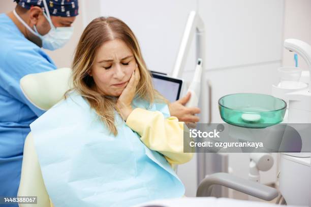 Young Woman Feeling Pain Holding Her Cheek With Hand At Dentists Officetoothache Concept Stock Photo - Download Image Now