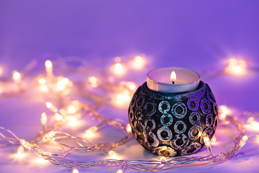 Beautiful burning candle and garlands with neon lighting, concept of romance and Christmas.