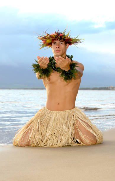 мужчина-танцор хула делает дающие жесты на коленях в песке. - hawaii islands maui hula dancing hula dancer стоковые фото и изображения