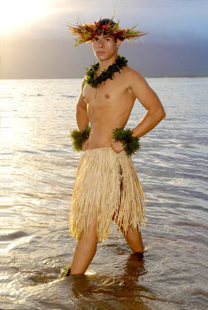 Handsome male hula dancer stands in the water as the sun sets. stock photo