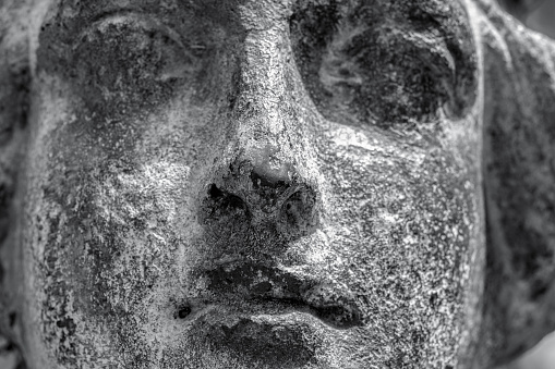 Close up black and white old bronze statue, face of angel, cemetery build in 1877 Sydney, full frame horizontal composition