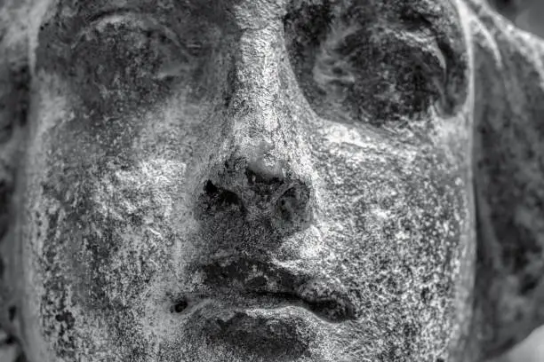 Photo of Closeup black and white old bronze statue, face of angel