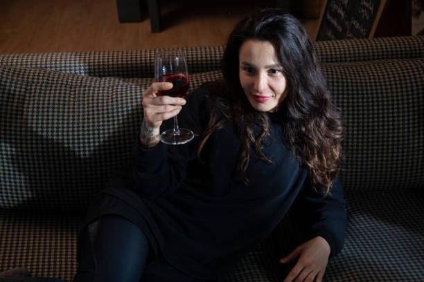 istock woman sitting on sofa drinking wine alone 1448391146