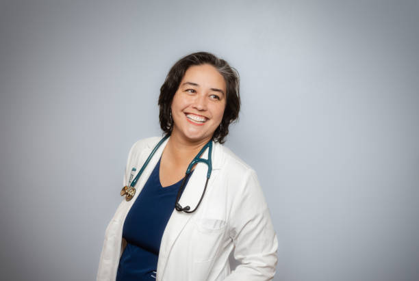 Studio Portrait - Female Doctor - Soft Grey Background - Positive Emotion - White Coat- Looking to the Side Studio Portrait - Female Doctor - Soft Grey Background - Positive Emotion - White Coat female doctor stock pictures, royalty-free photos & images