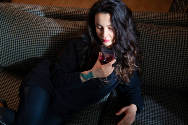 istock woman sitting on sofa drinking wine alone 1448391599