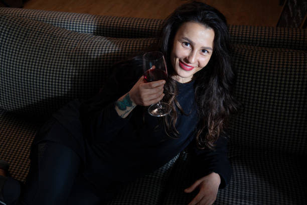 istock woman sitting on sofa drinking wine alone 1448391610