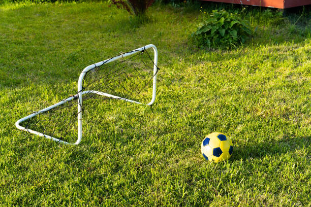 Schoolboy in a uniform kicking a soccer ball on mini goals isolated on white background