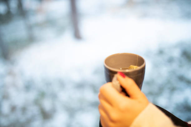 Close-up of the cup of tea that the woman is holding in her hands while sitting on the bed