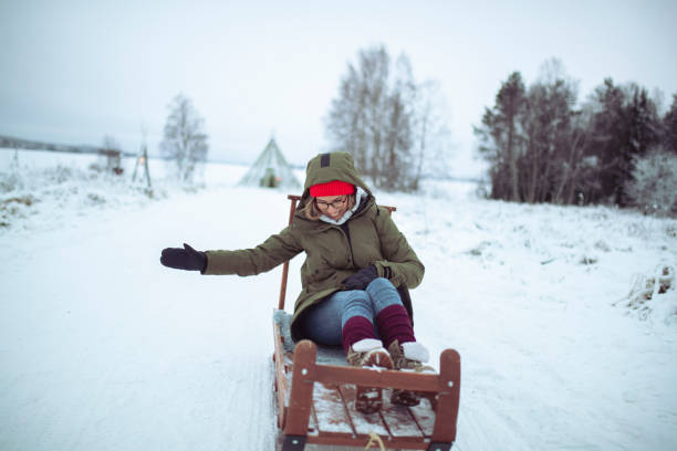 istock Smiling woman dressed in winter clothes having crazy fun sledding 1448393472