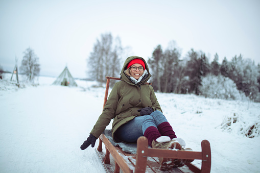A happy millennial woman enjoys winter magic, sledding all day