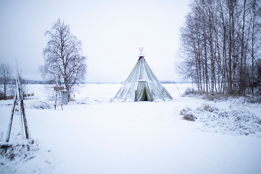 Snow covered traditional Lapland temporary shelter by the Sami People (lavvu, wigwam or kota) in snowy forest at day in Rovaniemi, Lapland, Finland, Europe wigwam)