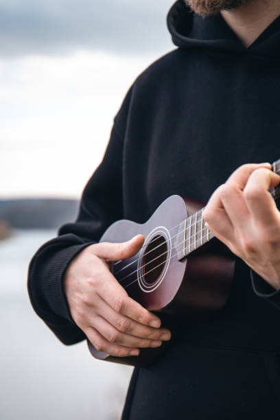 młody mężczyzna gra na gitarze ukulele w naturze na rozmytym tle. - playing an instrument vertical blurred motion outdoors zdjęcia i obrazy z banku zdjęć