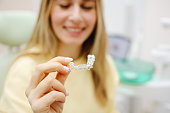 Dental invisible braces or silicone trainer in the hands of a young smiling women. Orthodontic concept - Invisalign