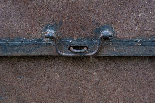 Old black iron metal latch on brown concrete background texture