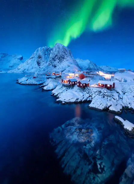Aurora Borealis. Northern Lights. View on the house in the Hamnoy village, Lofoten Islands, Norway. Landscape in winter time. Mountains and water.
