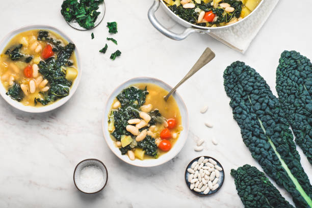 cavolo nero (cavolo nero o cavolo nero) minestrone con fagioli bianchi cannellini su fondo bianco. ricette invernali medicee toscane italiane. cibo vegetariano tradizionale sano, vista dall'alto - minestrone foto e immagini stock