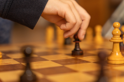 Soft focus of anonymous person moving pawn on board during chess game in daytime