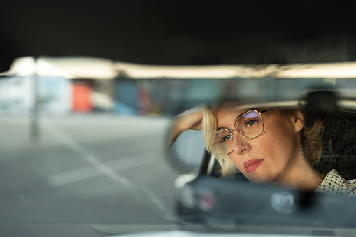 Rear view of serious business woman sitting in a car in traffic jam.