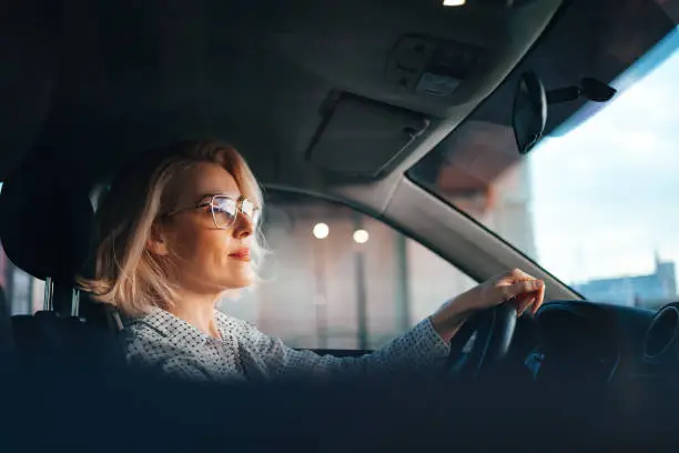 Smiling business woman traveling with her car around the city.