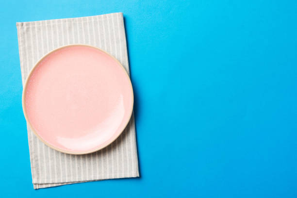 istock Top view on colored background empty round pink plate on tablecloth for food. Empty dish on napkin with space for your design 1448400512