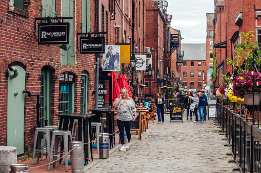 Portland, Maine, USA - A few people walking the cobbled street lined with shops and pubs in the Old Port district.