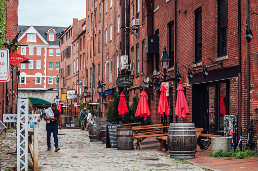 Portland, Maine, USA - A few people walking the cobbled street lined with shops and pubs in the Old Port district.
