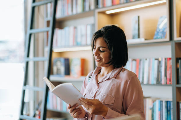 Woman reading a book in the library Woman reading a book in the library bookstore stock pictures, royalty-free photos & images