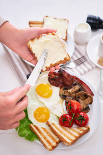 istock Fried eggs, bacon, tomato, toasted bread in white ceramic plate and cup of coffee 1448407829