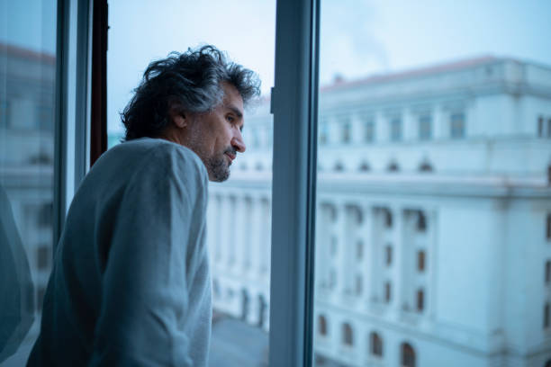 istock Urban lifestyle. Man looks from tall building window. 1448408983