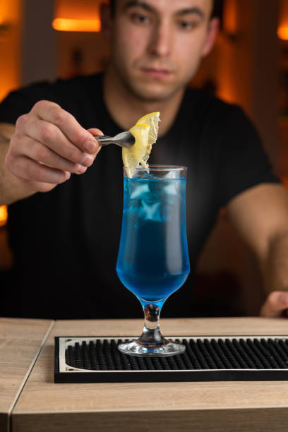 istock Bartender preparing Blue Lagoon cocktail decorated with lemon at the bar counter 1448409075