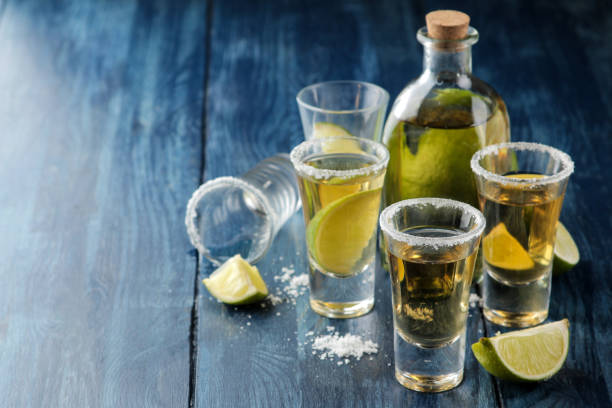 tequila dorée dans un verre avec du sel et de la chaux sur une table en bois bleu. boissons alcoolisées. - cocktail nobody close up fruit photos et images de collection