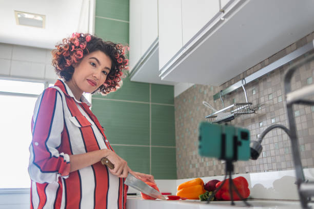 istock Young pregnant woman cutting vegetables while watching a video tutorial at the kitchen counter 1448409951