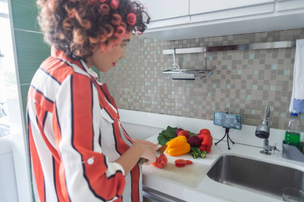 istock Young pregnant woman cutting vegetables while watching a video tutorial at the kitchen counter 1448410009