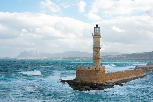 Beautiful travel image with entrance of the harbor Mandraki on Rhodes Island, Greece. Luxury yacht docked in port at the fortification. Famous deer statues at the entrance. Blue sky and clouds.