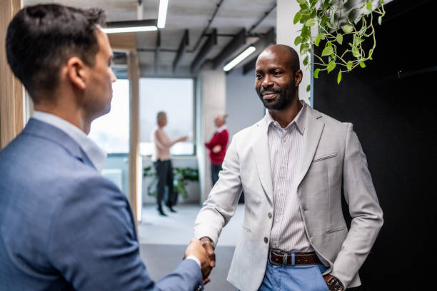 istock Businessmen shaking hands in an office 1448413602