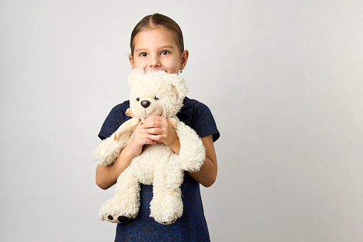 Portrait of little girl with white toy bear. Little girl holding teddy bear on white background with copy space
