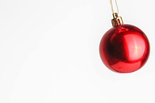 Photograph of a red christmas ornament ball on white background.