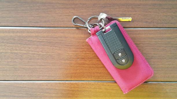 Car key remote with red canvas wallet on wooden background