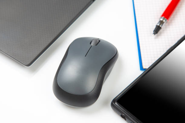 istock Computer wireless mouse next to a laptop on a white table close-up. electronic personal industry 1448426589