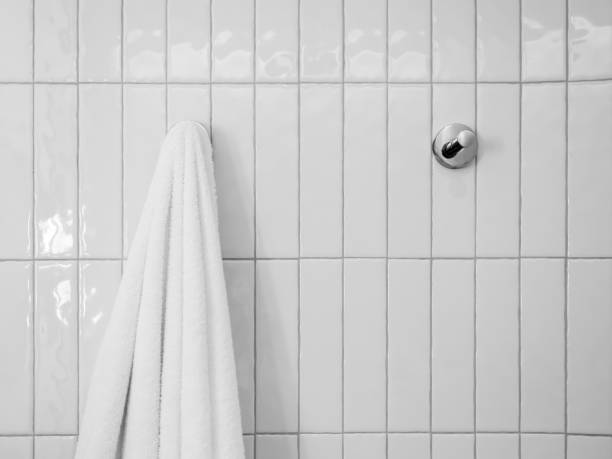istock Close-up white towel hanging on a hook, hanger on white mosaic pattern wall background in a hotel room with copy space, minimal style. 1448426597