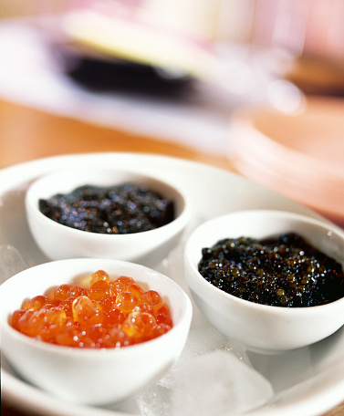 Red caviar in bowl close-up, salmon caviar on black stone background with copy space, seafood delicatessen