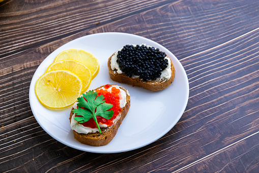 Open sandwiches with red and black caviar on a wooden board. Close-up shooting. The concept of fish delicacies.