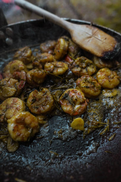 A large pan of shrimp in  is cooked above an open flame set in an outdoor A large pan of shrimp in  is cooked above an open flame set in an outdoor razor clam stock pictures, royalty-free photos & images